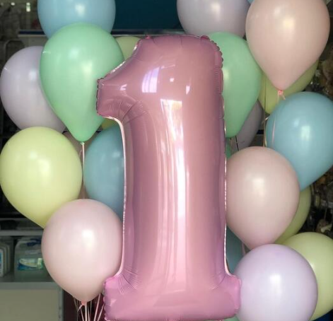Pink number 1 balloon surrounded by pastel balloons in a clusters